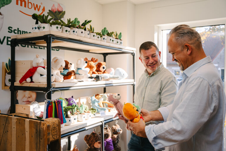 Hommes qui prennent des peluches sur une étagère